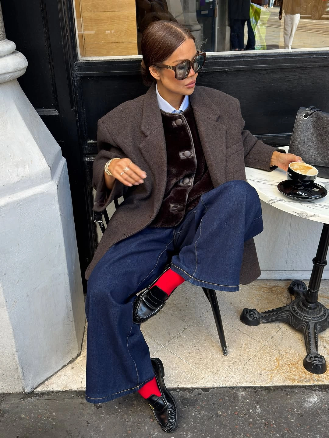 Dark brown blazer, glossy button-front layer, wide indigo jeans, red socks, and black loafers