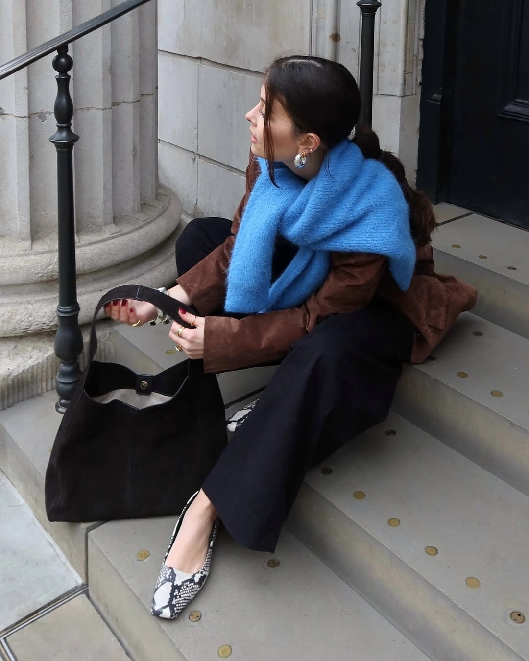 Oversized blue scarf over brown jacket with black trousers and patterned flats