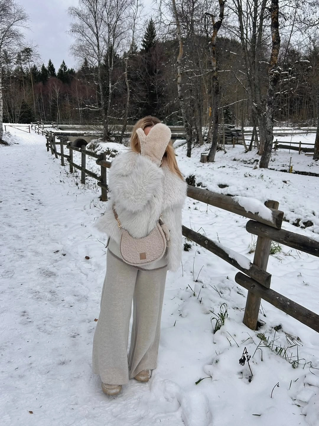 Short ivory shaggy outerwear, wide pale trousers, earmuffs, and blush handbag