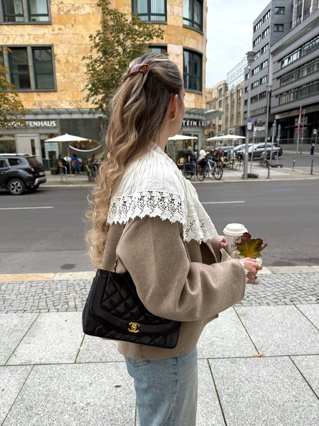 Taupe sweater with ivory lace-edged shoulder layer, pale jeans, and black bag