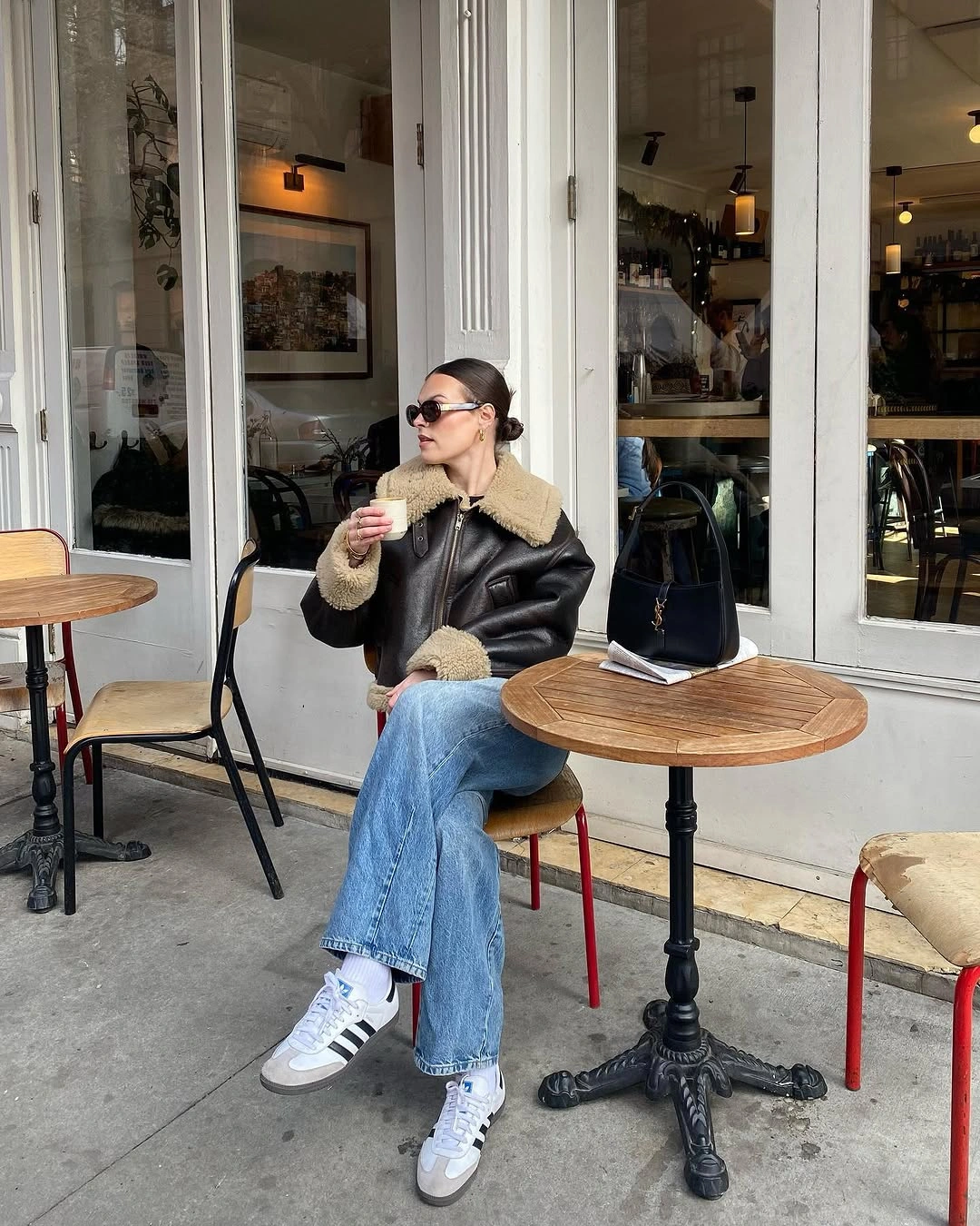 Dark leather-look jacket with tan plush trim, blue jeans, and striped sneakers