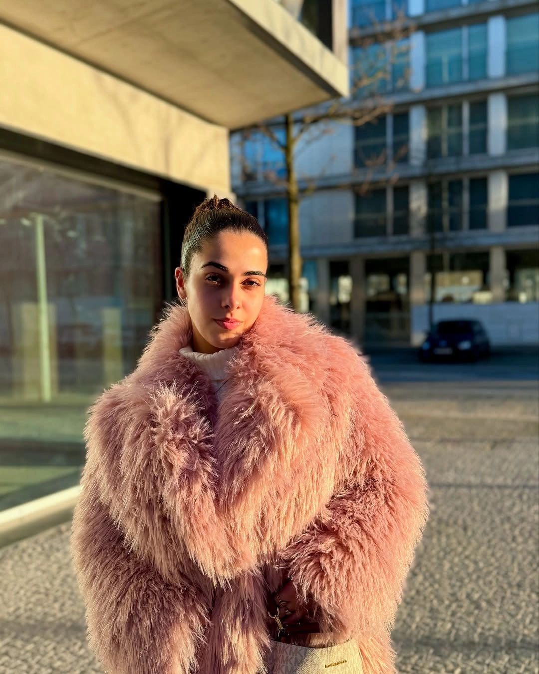 Oversized dusty pink shaggy jacket over a pale high neckline outdoors