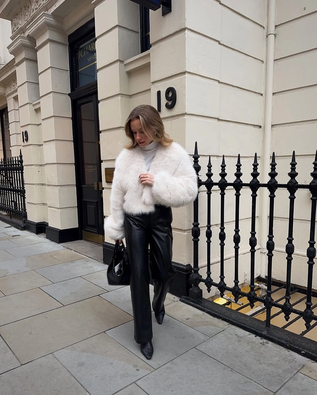 Short white fluffy jacket with glossy black trousers and pointed shoes