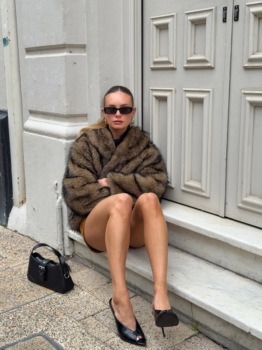 Brown voluminous textured jacket with black heels, sunglasses, and handbag