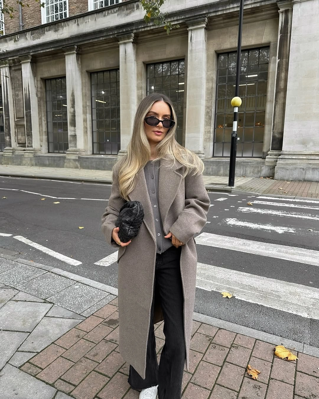 Long taupe gray coat over gray cardigan and dark wide trousers