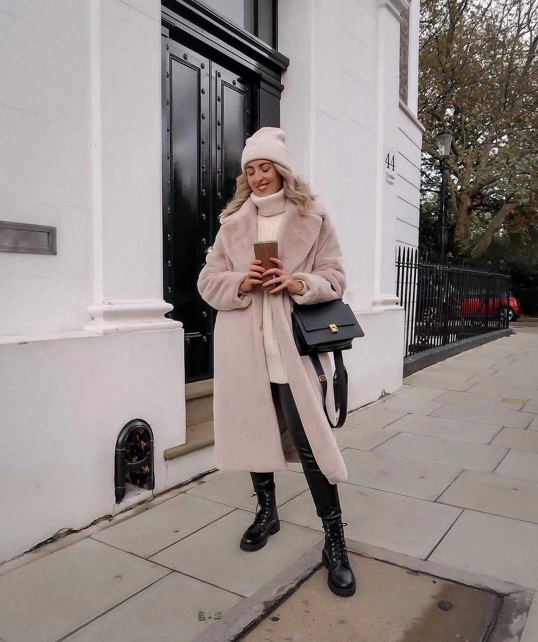 Pale blush coat, cream scarf, knit hat, dark pants, and black boots.