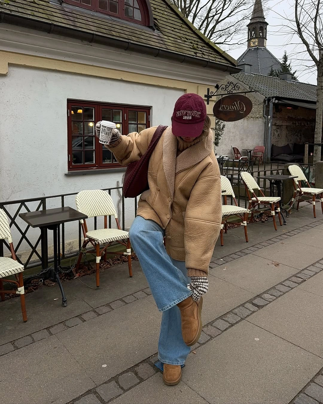 Oversized tan jacket, burgundy cap and bag, wide jeans, and tan shoes.
