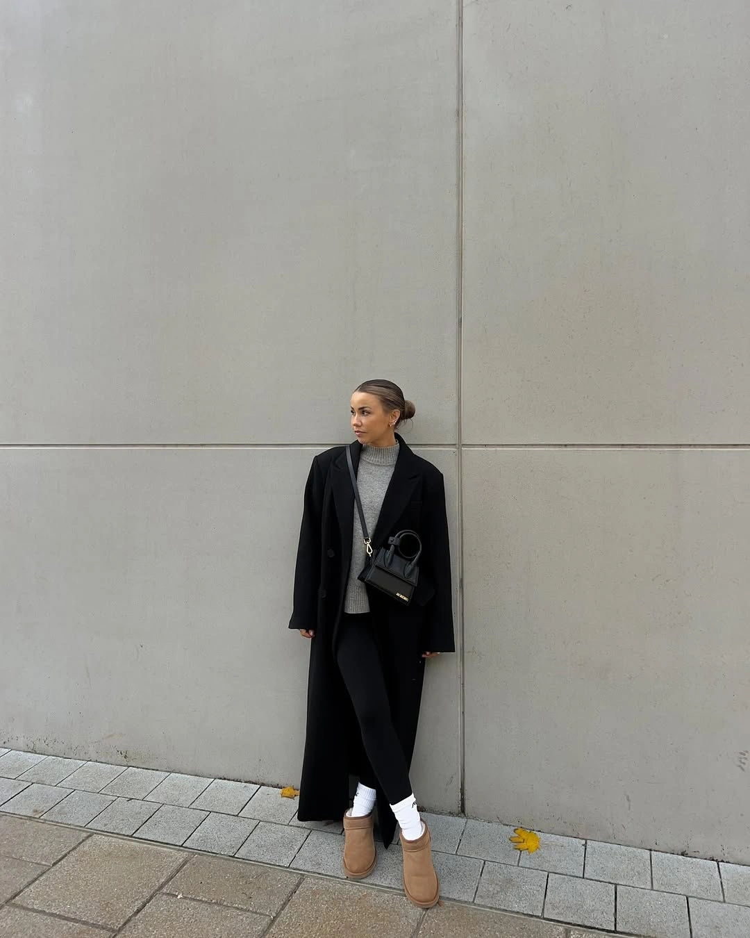 Long black coat, gray high-neck top, dark pants, white socks, and tan boots.