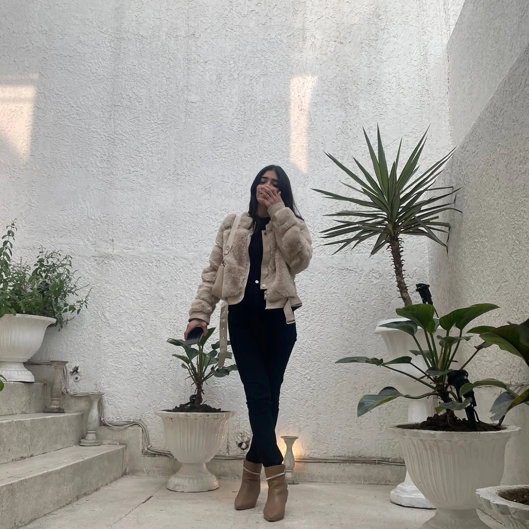 Beige fuzzy cropped jacket, black top and pants, and taupe ankle boots.