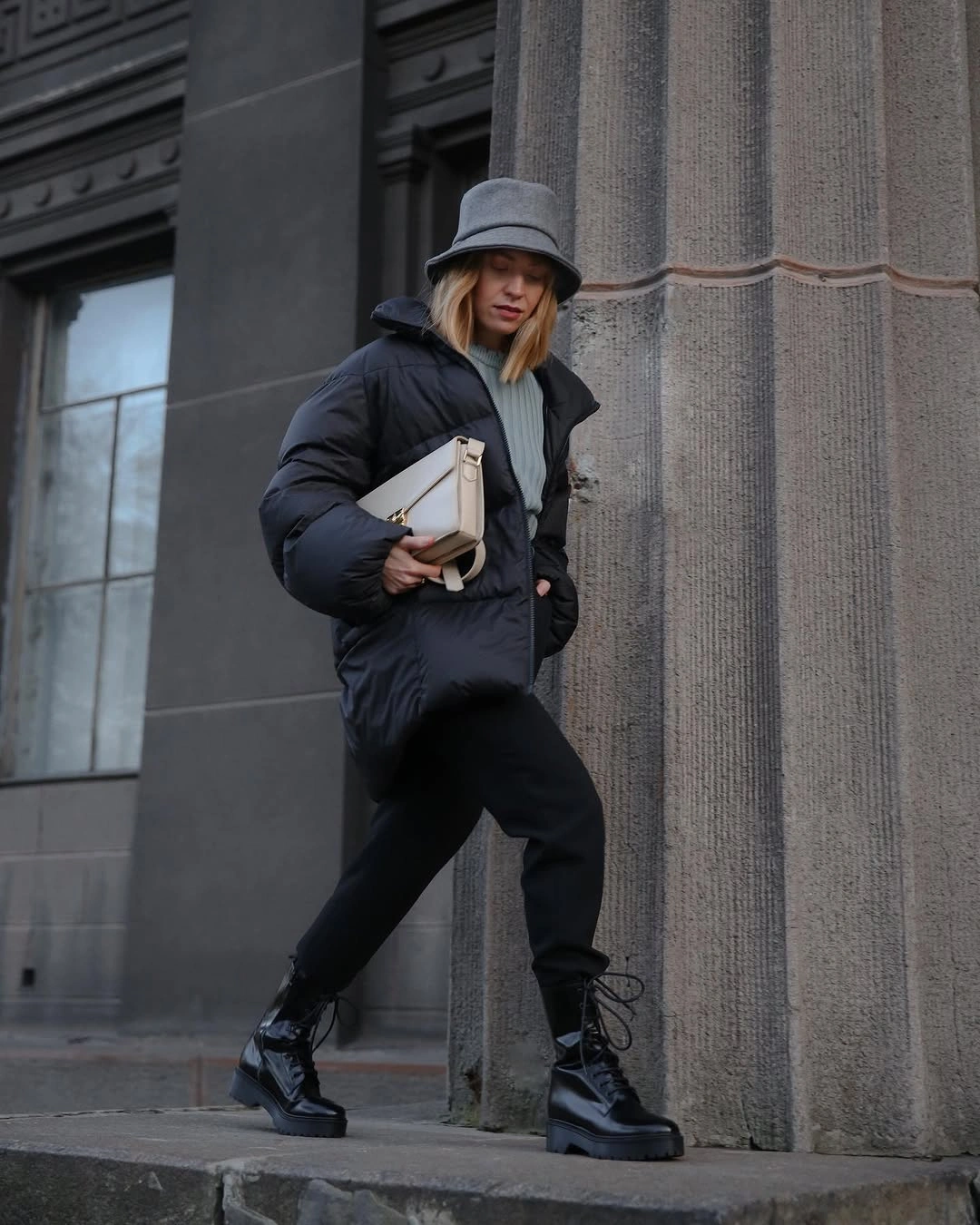 Black puffer jacket, dark pants, gray bucket hat, and black chunky boots