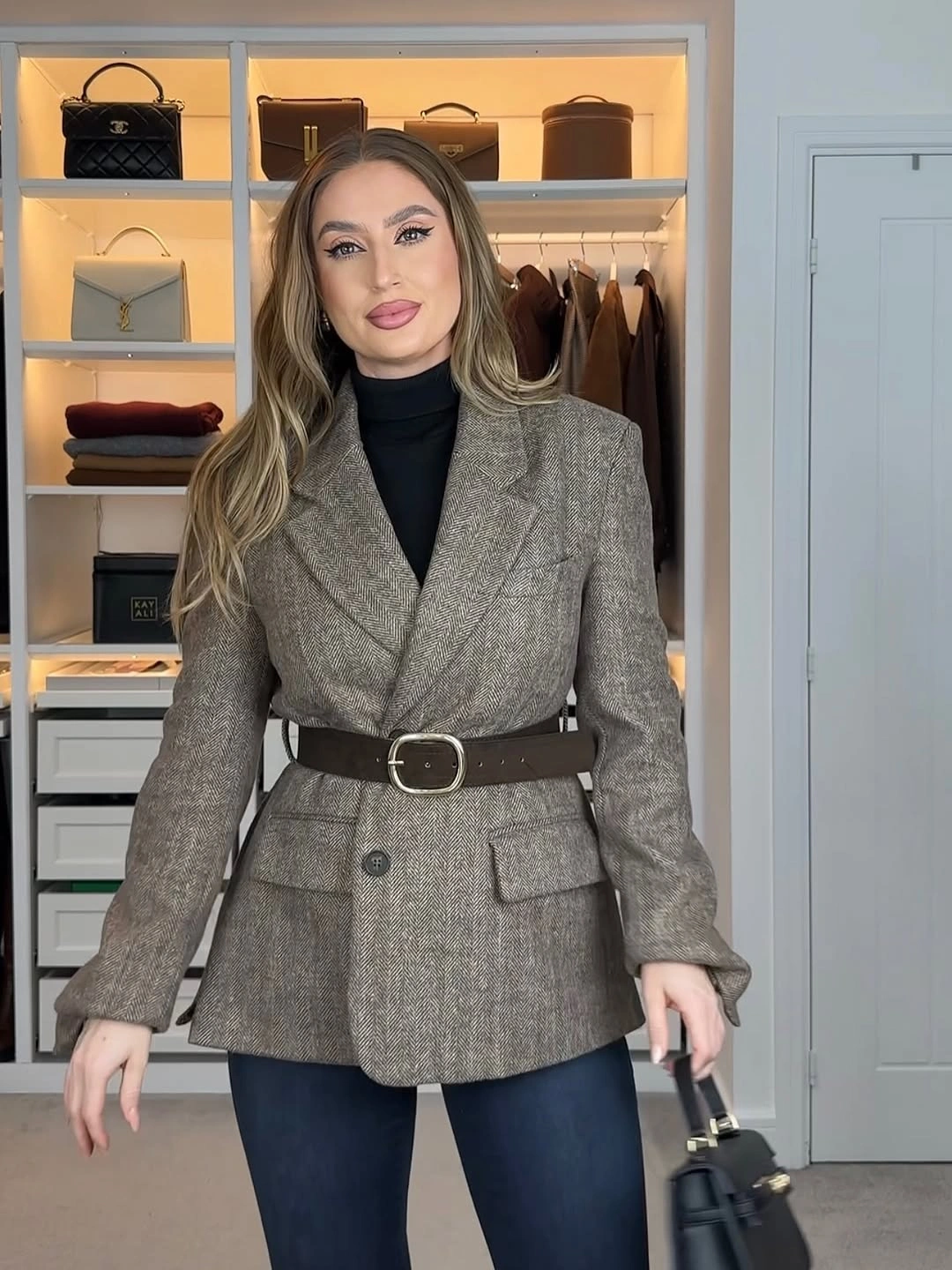 Gray textured belted blazer, black turtleneck, dark jeans, and black handbag
