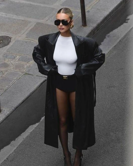 Long black coat, fitted white top, black shorts, and sheer tights