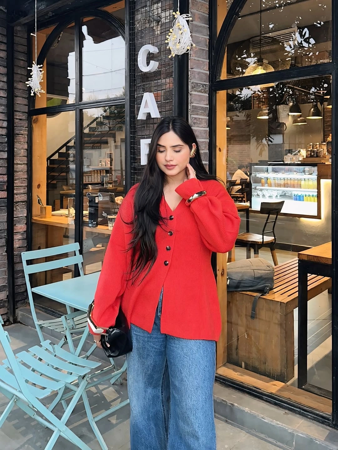 Bright red buttoned cardigan, loose blue jeans, and small black bag