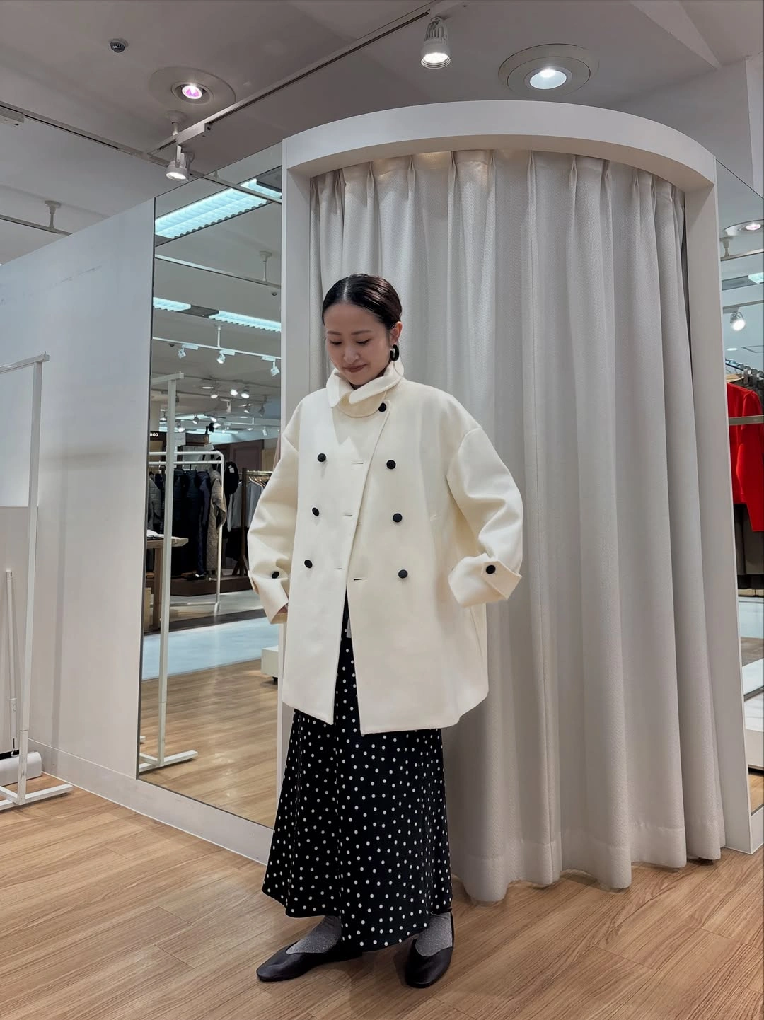 Ivory double-breasted coat, black dotted long skirt, gray socks, and dark flats