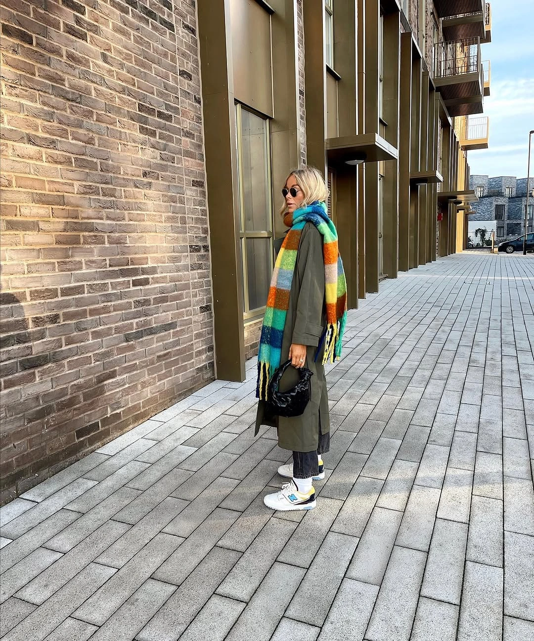 Olive long coat with striped scarf, dark jeans and white sneakers