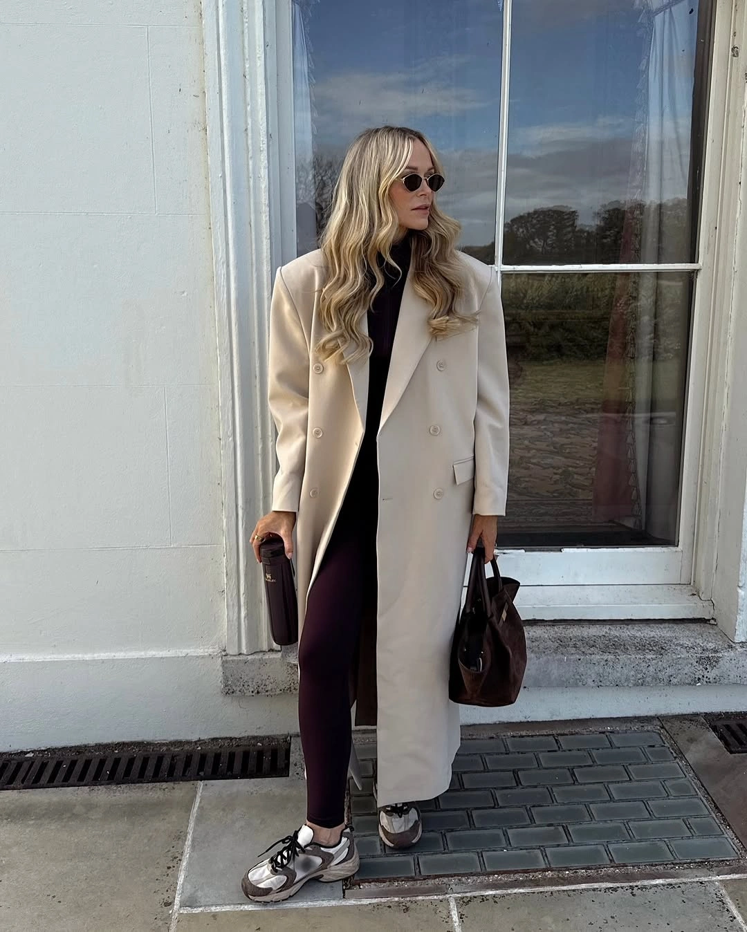 Cream long coat with burgundy leggings and chunky gray sneakers
