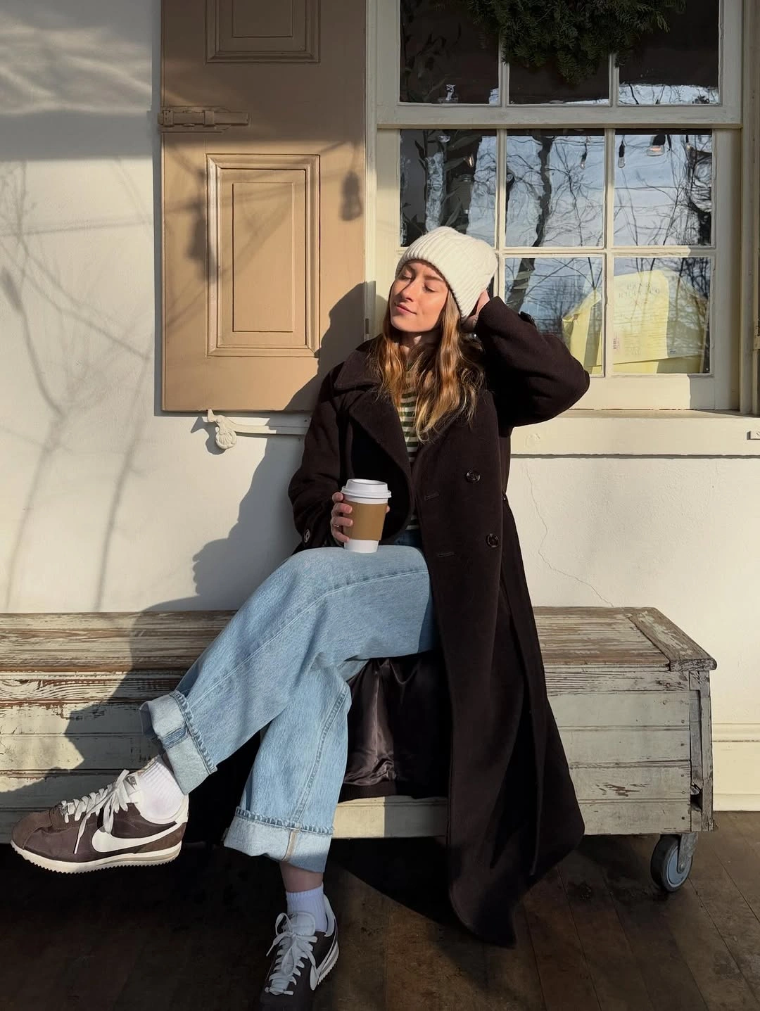 Dark long coat with cuffed jeans, beanie and sneakers