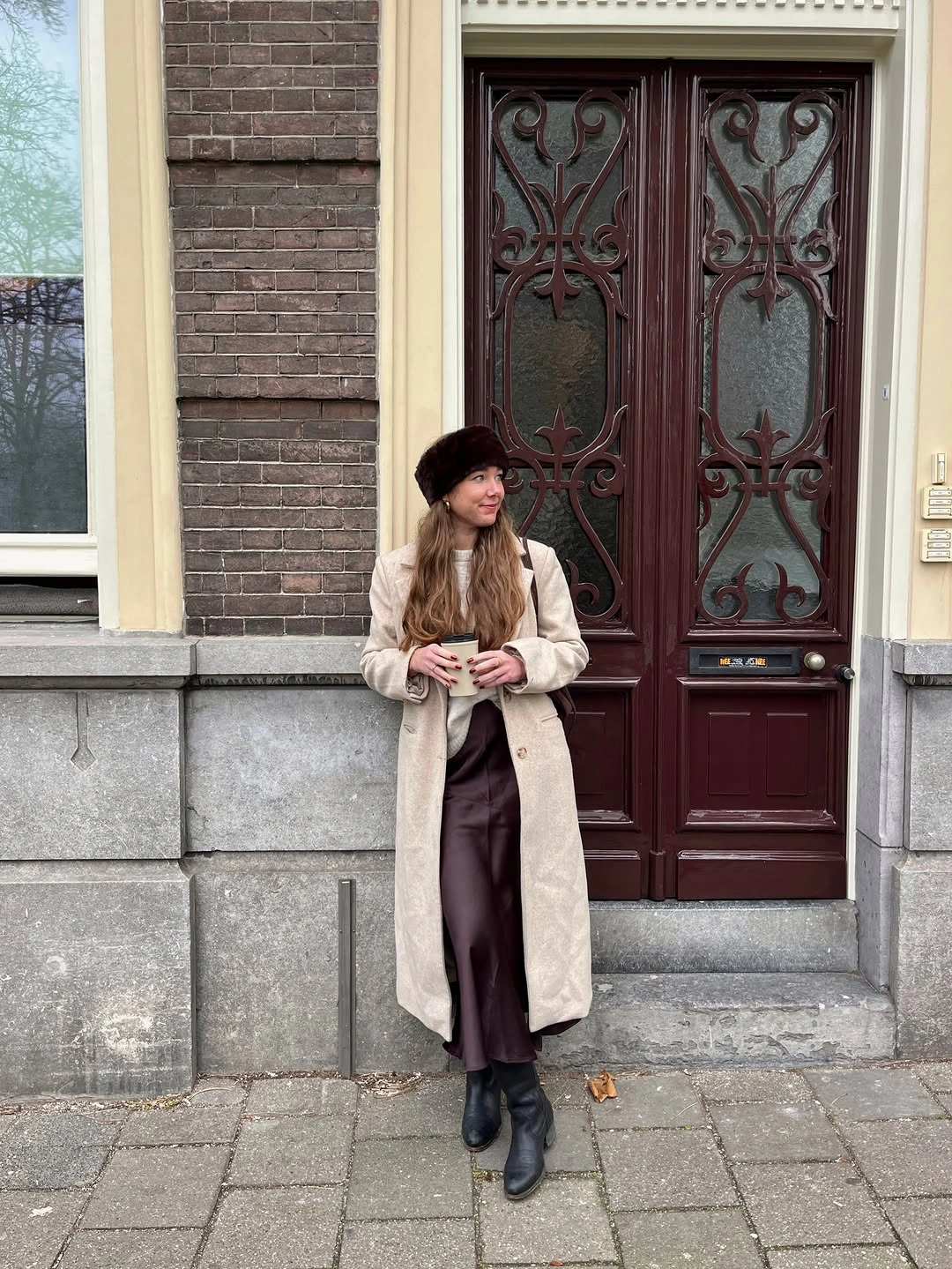 Beige long coat with brown skirt, dark plush hat and black boots
