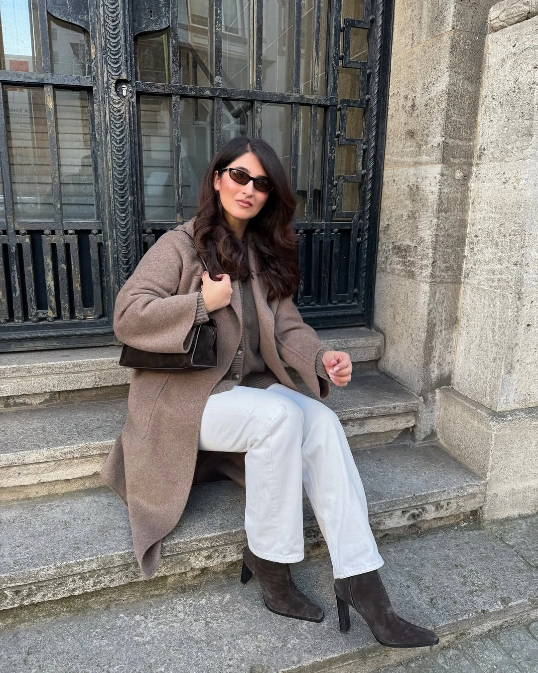 Taupe coat with ribbed cardigan, white trousers and brown ankle boots