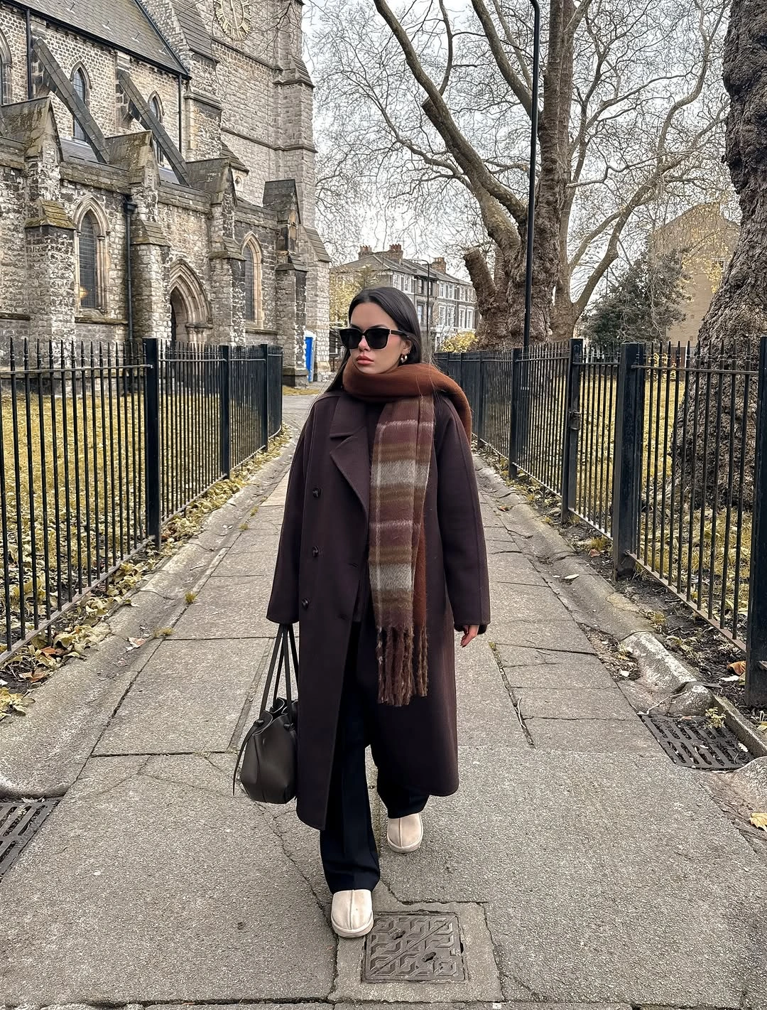 Dark brown long coat with striped scarf and pale shoes