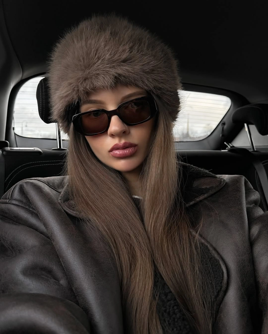 Brown plush hat with dark sunglasses and structured jacket